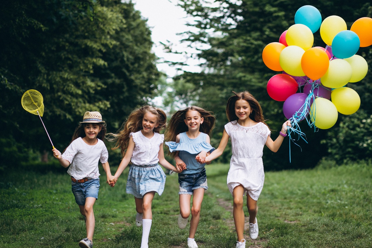 Children running with balloons in a park