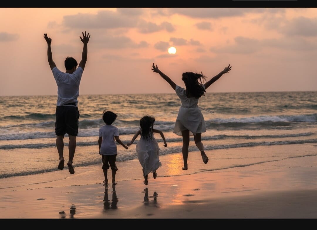 Family jumping on a beach at sunset